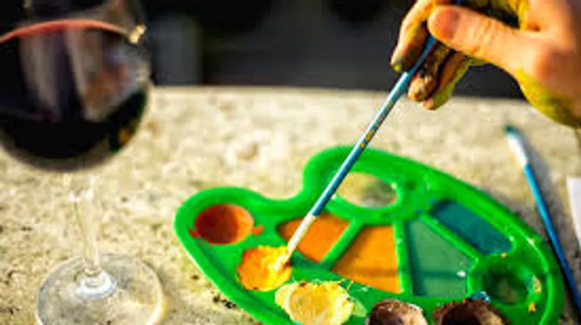 Farbenpalette und Weinglas auf Tisch.