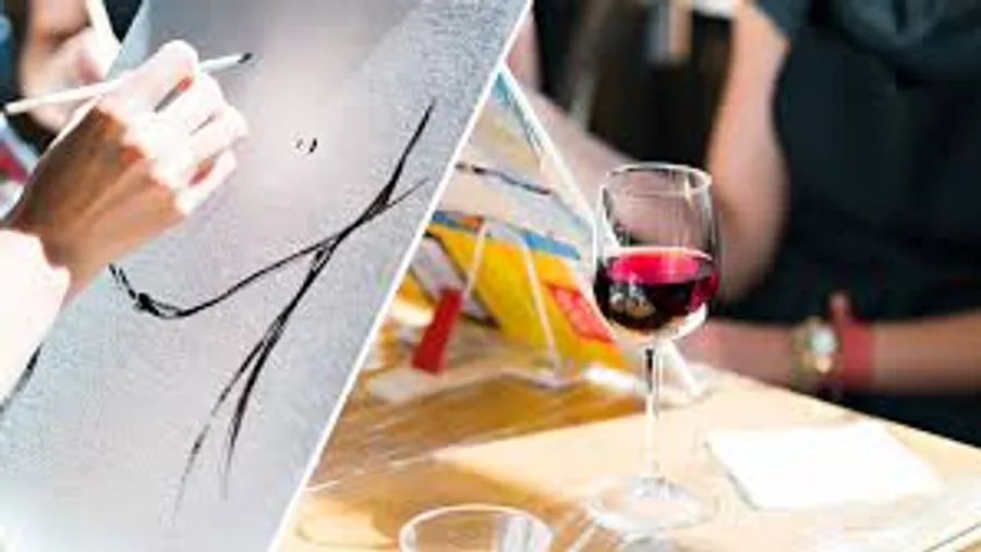 Person painting with wine glass nearby.