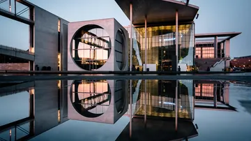 Modernes Gebäude mit Wasserreflexion bei Dämmerung.