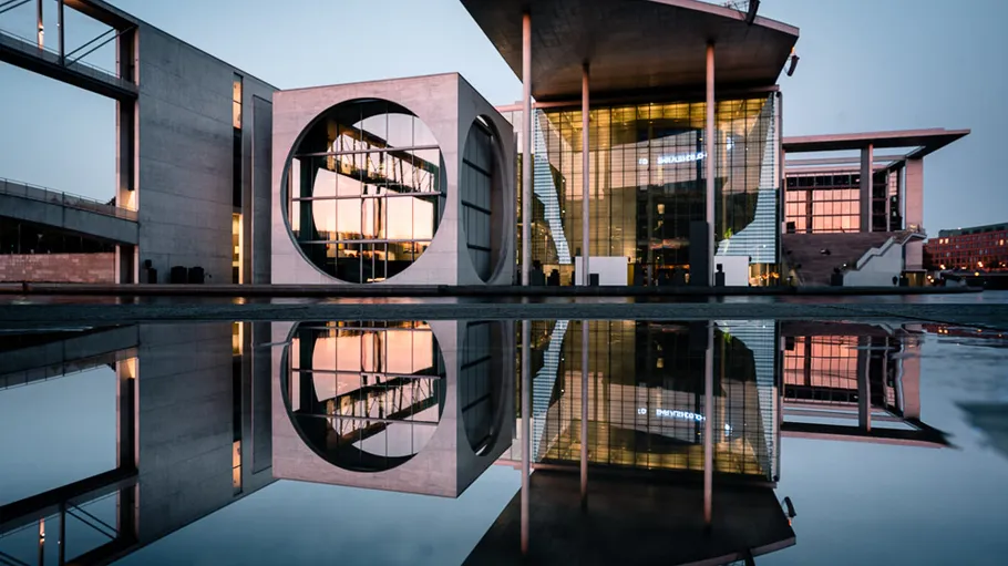 Modernes Gebäude mit Wasserreflexion bei Dämmerung.