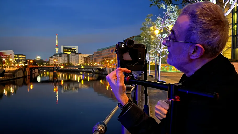 Mann fotografiert nachts Stadtlandschaft am Fluss.