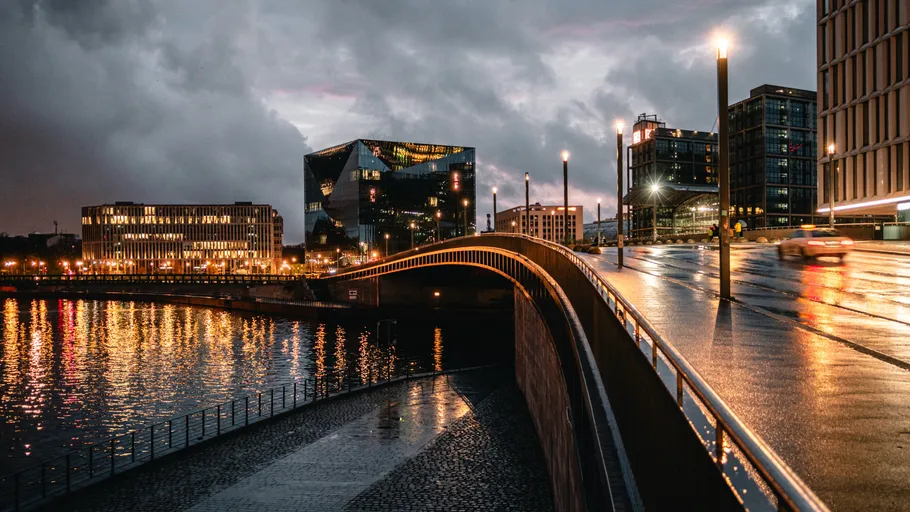 Stylish bridge illuminated at night, city buildings surrounding.