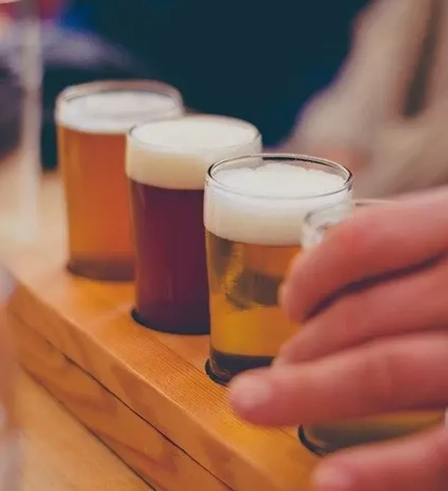 Drei Biergläser auf einem Holztablett.