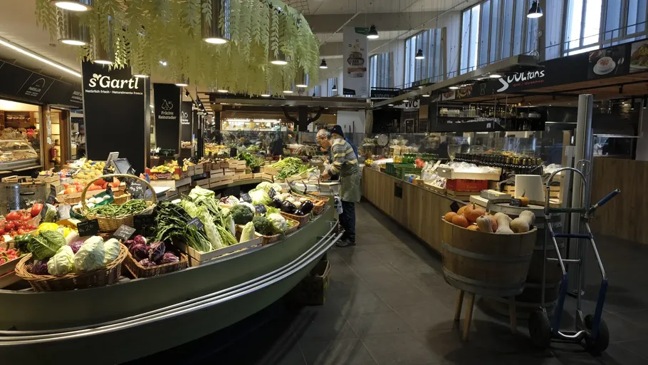 Indoor market with fresh vegetables on display.