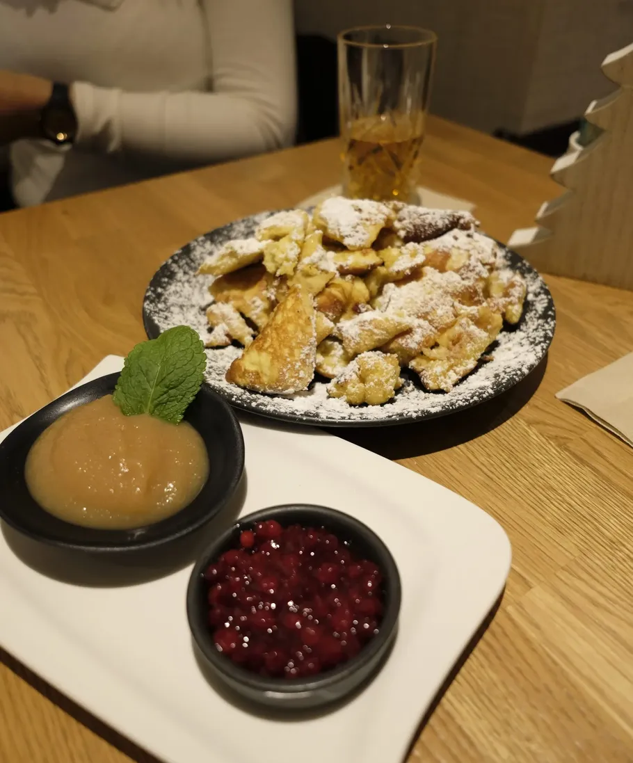 Kaiserschmarrn mit Apfelmus und Beeren auf Tisch.