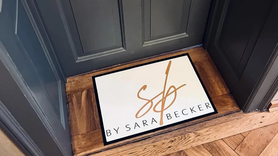Doormat with 'By Sara Becker' inside doorway.