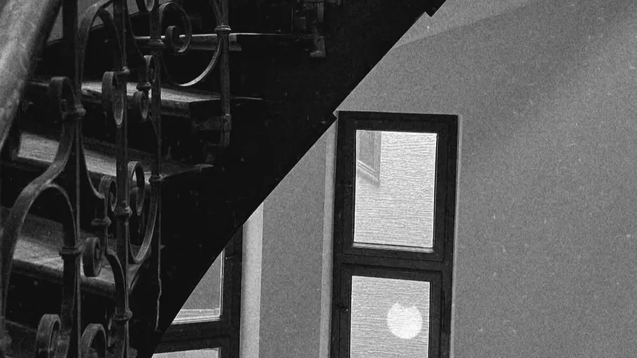 Ornate staircase beside large window inside building.