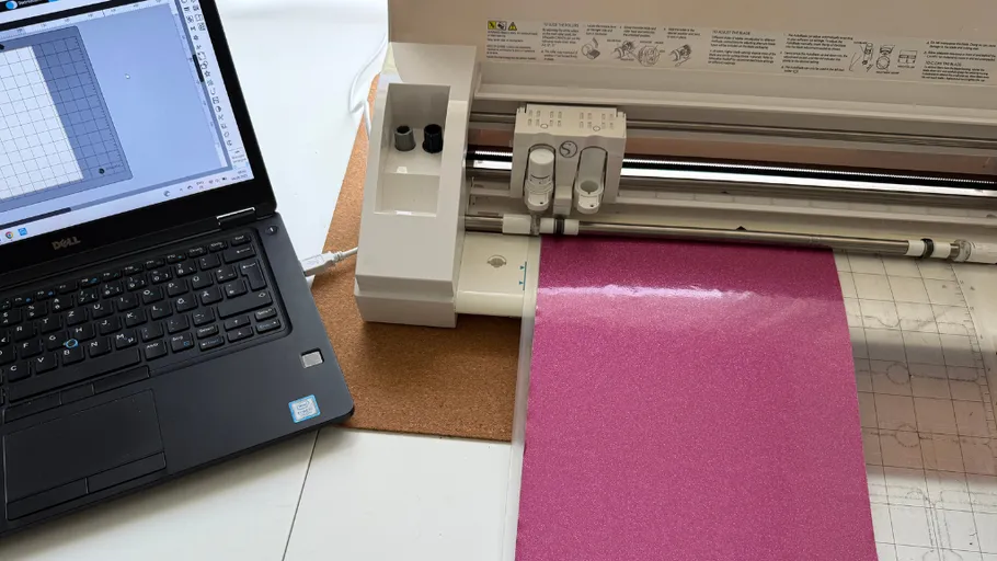Laptop connected to cutting machine, pink material.