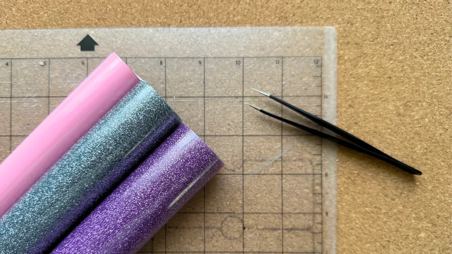 Bunte Vinylrollen und Pinzette auf Schneidematte.