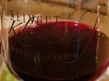Wine glass with red wine on a wooden table.