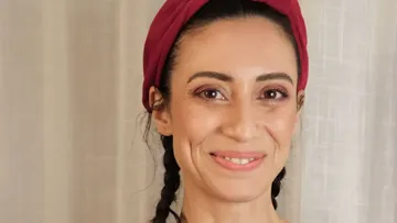 Smiling woman with braided hair indoors.