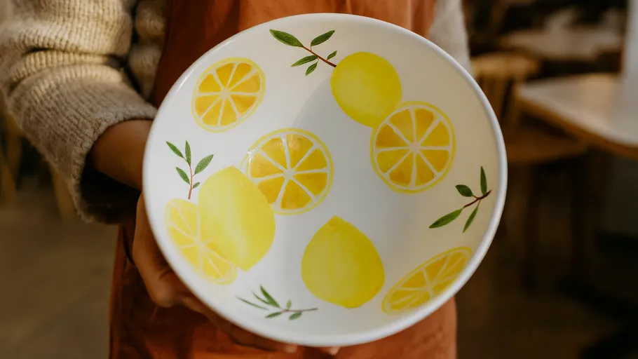 Person holding a lemon-patterned bowl indoors.