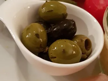 Green and black olives in a white bowl.