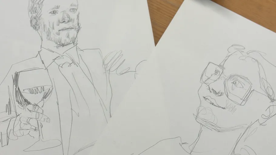 Skizzen von zwei Personen auf Papier, Tischhintergrund.