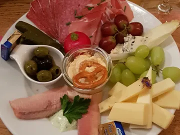 A starter with sausage, cheese and fresh fruit.