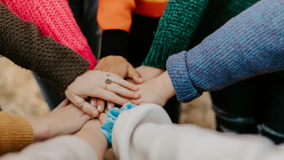 Hands stacked in a teamwork gesture outdoors.