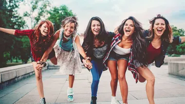 Fünf Frauen lachen und posieren im Freien.