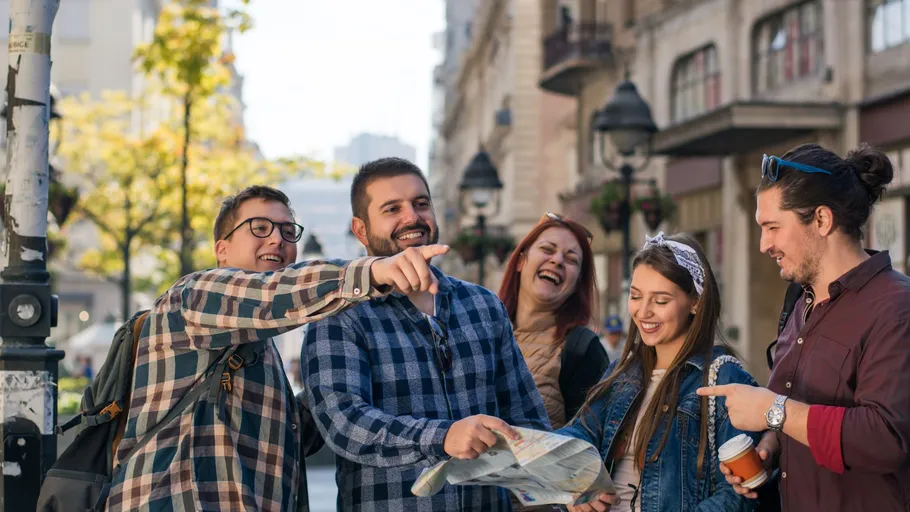 Group of friends laughing and reading map outdoors.