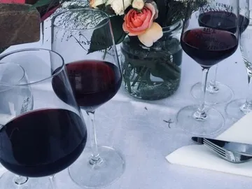 Rotweingläser stehen auf einem Tisch mit Blumen.
