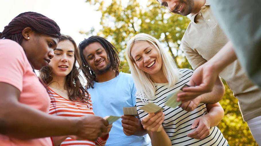 Group of people outdoors playing cards together.
