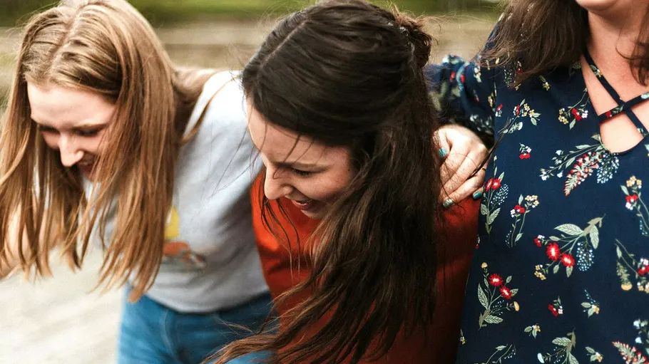 Three laughing women in casual outdoor setting.