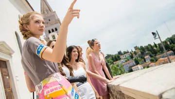 Women on balcony, one points into distance.