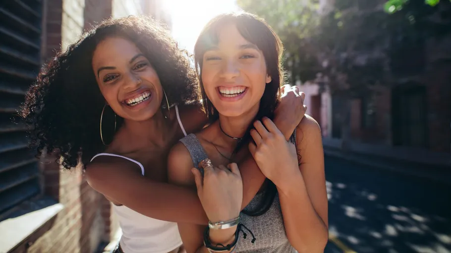 Two women hugging and smiling outdoors.