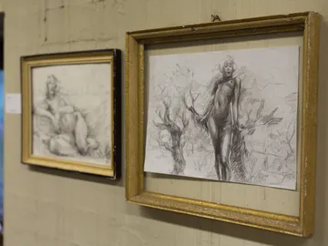 Two drawings in golden frames on a wall.