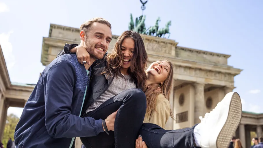 Three friends smiling at Brandenburg Gate.