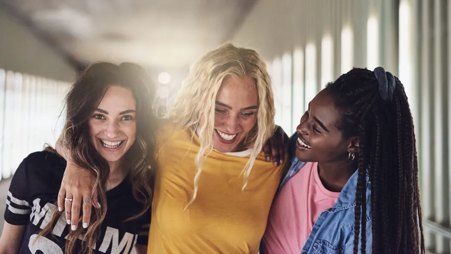 Three women smiling in a corridor.