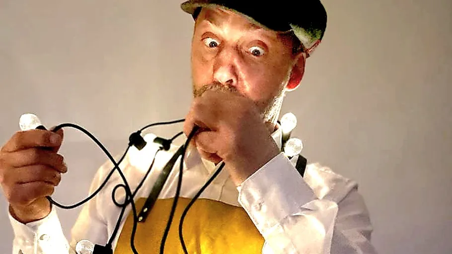 Surprised man holds and bites string lights.