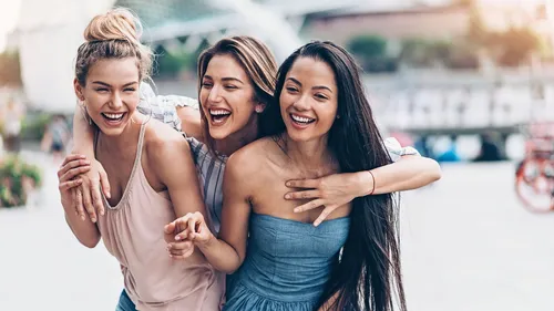 Three women laughing outdoors together.