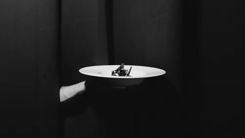 Hand hält Teller mit Dessert im dunklen Raum.