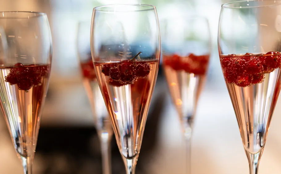Champagne glasses with berries inside, blurred background.