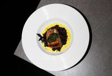 Teller mit Fleisch, Sauce und Reis auf Tisch.