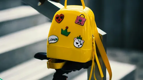 Gelber Rucksack mit Abzeichen auf einer Stufe.