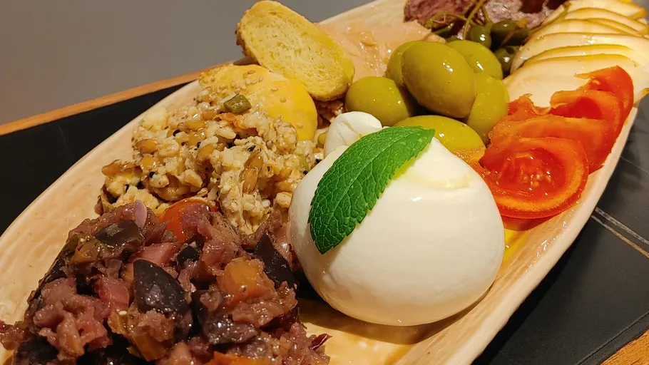 Käse und Oliven auf einer Platte mit Gemüse.