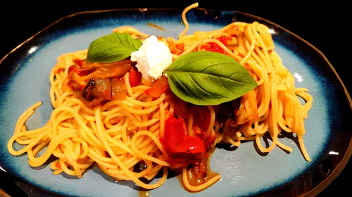 Spaghetti mit Basilikum und Ricotta auf blauer Platte.