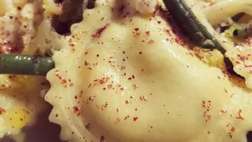 Ravioli mit roten Paprikaflocken und grünen Bohnen.
