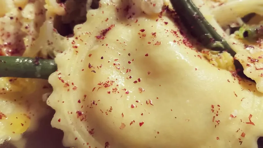 Ravioli mit roten Paprikaflocken und grünen Bohnen.