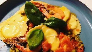 Ravioli and prawns garnished with basil leaves.