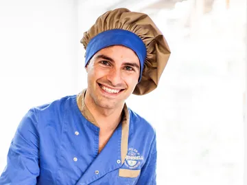 Smiling chef in blue uniform indoors.
