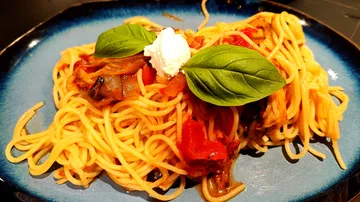 Spaghetti mit Basilikum, Sauce und Käse auf Teller.