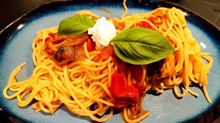 Spaghetti with basil, sauce, and cheese on plate.