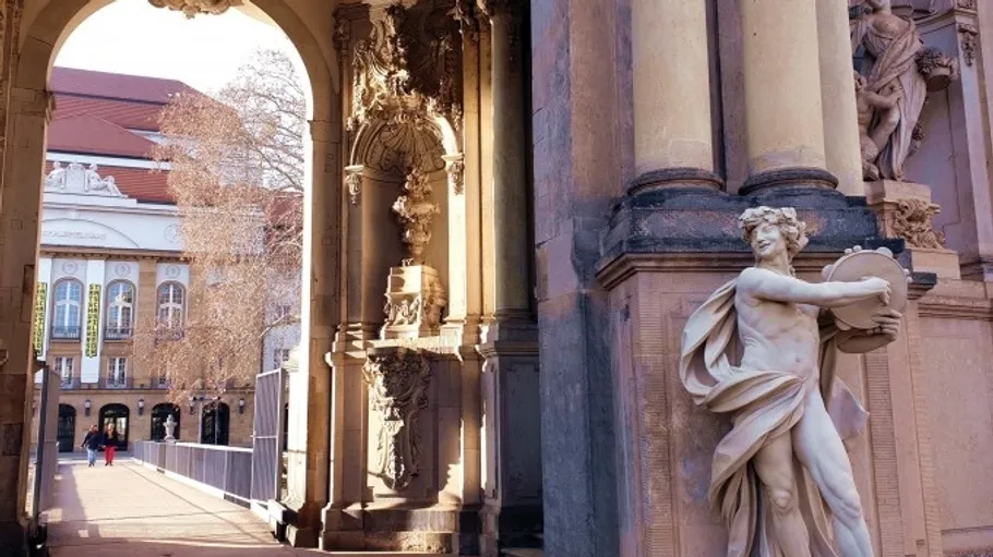 Statue neben verziertem Torbogen, entferntes Gebäude sichtbar.