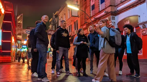 Gruppe lauscht Führer auf beleuchteter Straße.