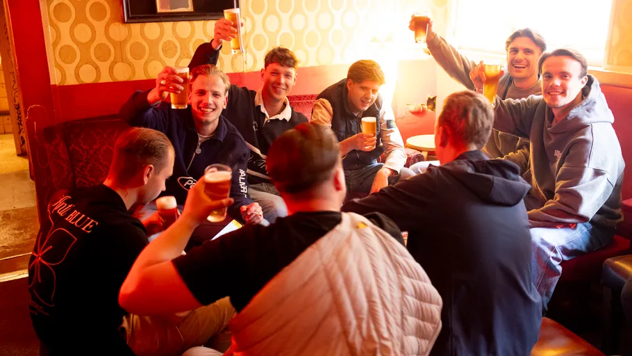 Gruppe von Leuten hebt Getränke in einer Bar.