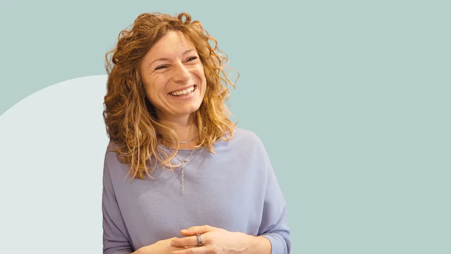 Smiling woman with curly hair, light blue background.