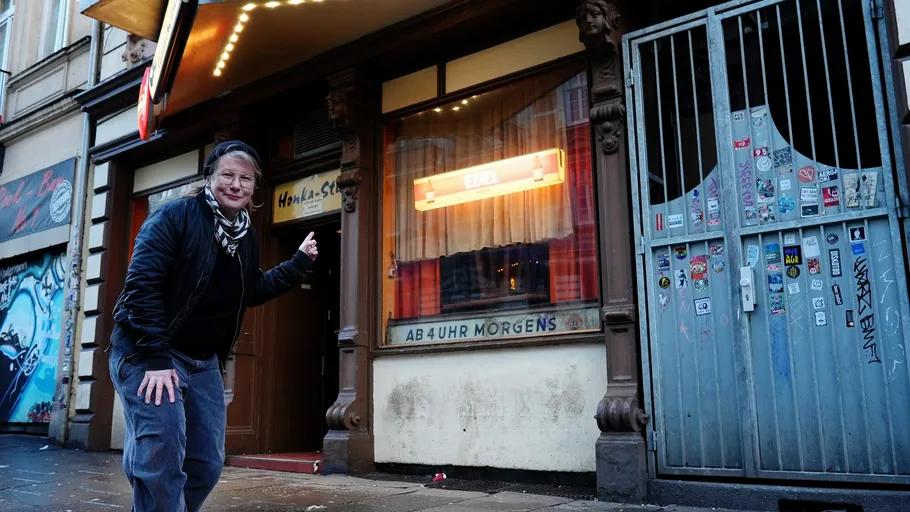 Person pointing at a bar entrance on street.