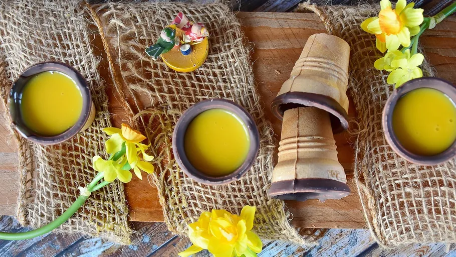 Bunte Tassen mit gelben Getränken, dekoriert mit Blumen.